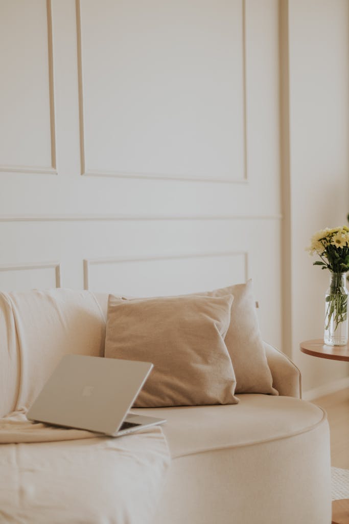 A serene and stylish home office with a neutral aesthetic featuring a laptop and cozy seating.